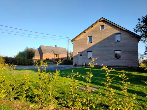 a large barn sitting in a field next to a house at Le refuge de Julia in La Roche-en-Ardenne