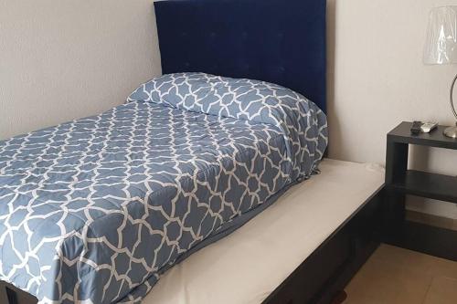 a bed with a blue and white comforter on it at Increible Apartment with beach Monterrey/Apodaca in Monterrey
