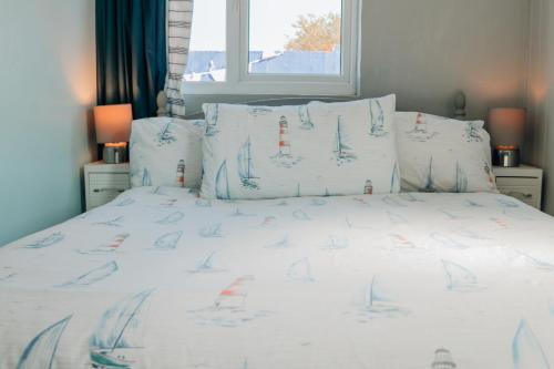 a bed with white sheets and pillows with sailboats on it at Houseboat Heyvon in Bembridge