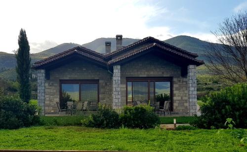a small stone house with mountains in the background at Lithos Villas in Amfiklia