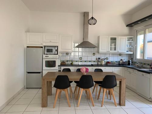 une cuisine avec une table en bois et des chaises noires dans l'établissement Mimizan Plage Grande maison bord de mer, à Mimizan