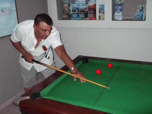 a man playing pool with a cue on a pool table at Luxor Residence Guesthouse in Belle Mare