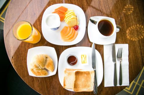 a table with plates of breakfast foods and a cup of coffee at The View Hotel by Covalia in San Luis Potosí