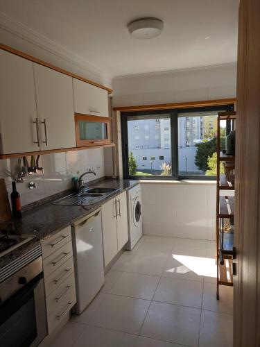 a kitchen with white cabinets and a large window at Apartamento do Paço do Lumiar in Lisbon