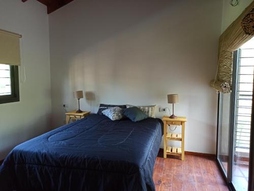 Un dormitorio con una cama azul y dos mesitas de noche. en Papa Ruku, en Villa Ciudad Parque