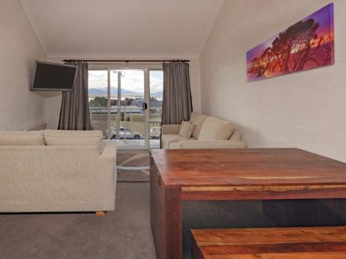 a living room with a couch and a table at Parkwood 6 - 2BR Split Lvl Apartment l Spa Bath l BBQ l Central Location in Jindabyne