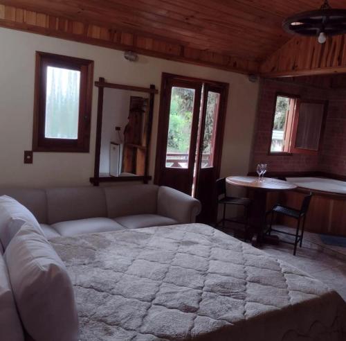uma sala de estar com uma cama grande e uma mesa em Pousada Chales Monte Verde em Monte Verde