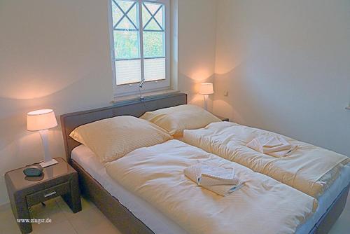 a bed in a room with two lamps and a window at Villa Morgentied, FW 1 in Zingst