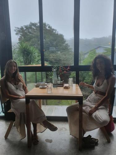 two women sitting at a table in front of a window at OutBox Inn in Monteverde Costa Rica