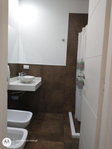 uma casa de banho com um lavatório branco e um WC. em Departamento Serrano em Tandil