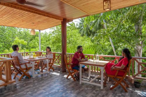 
three children sitting at a picnic table with umbrellas at Ostrov Hotel in Ukulhas
