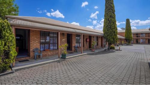 a brick building with trees and chairs in front of it at Rodney Motor Inn in Mooroopna