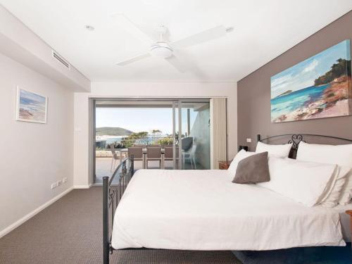 a bedroom with a large bed and a balcony at Barefoot Bliss 4 in Fingal Bay