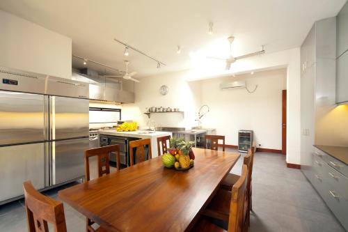 a large kitchen with a wooden table with chairs and a kitchen with stainless steel at Nisala Villas in Mirissa