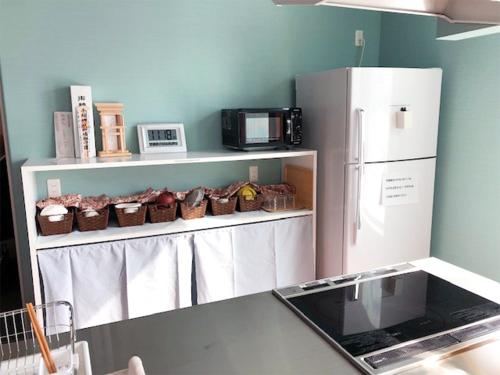 a kitchen with a white refrigerator and baskets of food at Choine Hotel Sapporo Teine in Sapporo