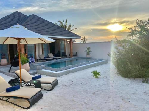 a house with a swimming pool with chairs and an umbrella at Brennia Kottefaru Maldives in Raa Atoll