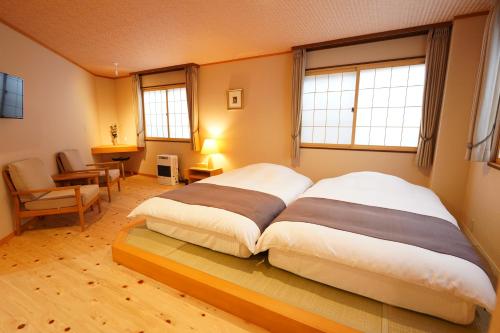 een groot bed in een kamer met 2 ramen bij Soumeian in Kusatsu
