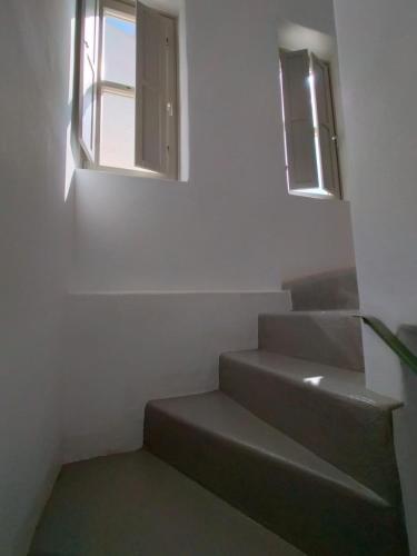 a staircase with two windows in a white room at Chora Elegant Traditional House in Amorgos