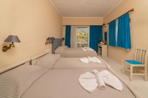 a hotel room with a bed, chair, and nightstand at Matilda Hotel in Vasilikos