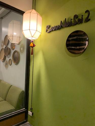 a room with a green wall with a lamp and a sign at Baannaisoi2home in Chiang Mai