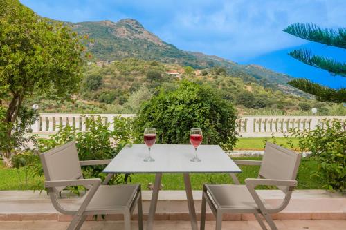 two glasses of wine sitting on a table on a patio at Matilda Hotel in Vasilikos