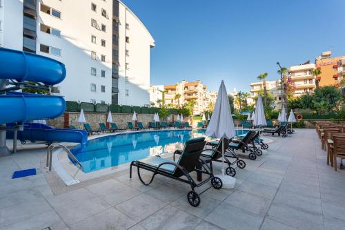 einen Pool mit Liegestühlen und Sonnenschirmen neben einem Gebäude in der Unterkunft Kaila City Hotel in Alanya