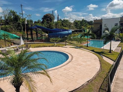 a swimming pool in a park with a palm tree at Apartasol, Eje cafetero Reservas de la Colina 111B in La Tebaida