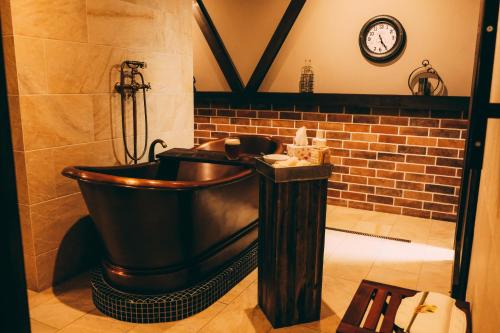 a bath tub in a bathroom with a clock on the wall at Penzión Flámm in Rajecké Teplice