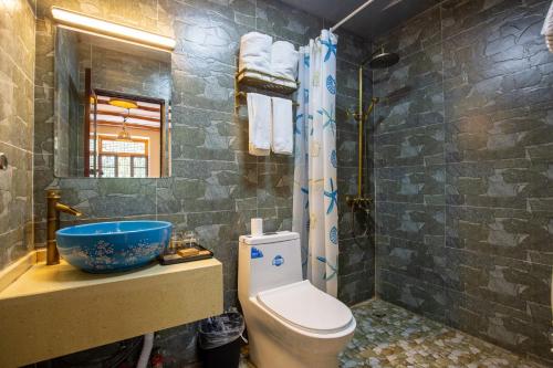 a bathroom with a toilet and a sink and a tub at Jiaju Legend Homestay in Danba