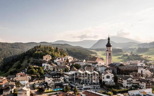 a town in the mountains with a clock tower at Hotel Cavallino D'Oro Bed&Breakfast in Castelrotto