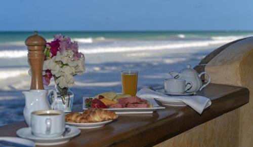 uma mesa com pequeno almoço de café e comida na praia em Blue Marlin Beach Hotel em Praia de Diani