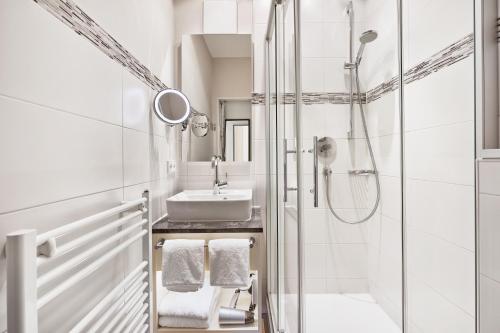 a white bathroom with a sink and a shower at Königshof Hotel Resort in Oberstaufen