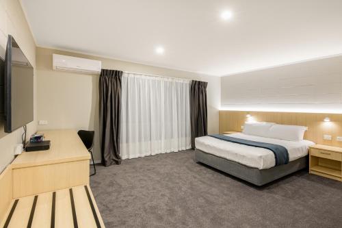 um quarto de hotel com uma cama e uma televisão de ecrã plano em Takapuna International Motor Lodge em Auckland