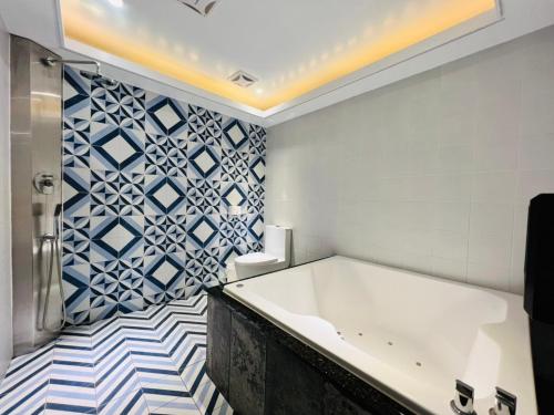 a bathroom with a tub and blue and white tiles at Formosa Motel & Inn in Changhua City