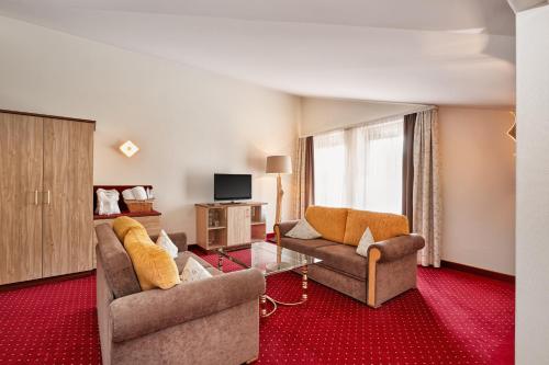 a living room with two couches and a tv at Königshof Hotel Resort in Oberstaufen
