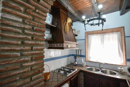 - une cuisine avec un mur en briques et un évier dans l'établissement Tu Villa Rural Acequia 5 Dormitorios, à Alhaurín el Grande