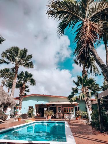 a pool in front of a building with palm trees at Arubiana Inn Hotel in Palm-Eagle Beach