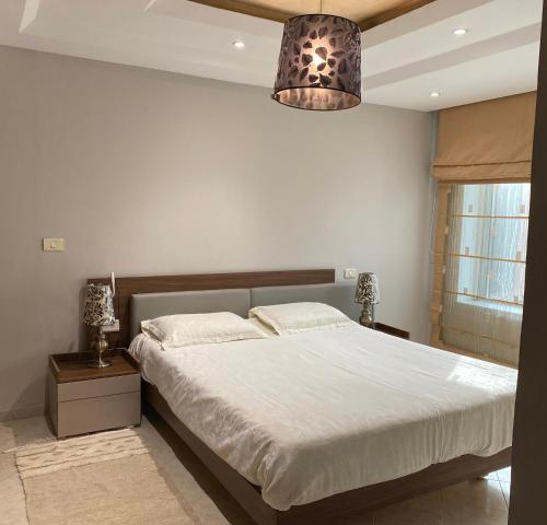 a bedroom with a large bed and a chandelier at Lac Palace Luxury Apartment-2 Bdr in Tunis