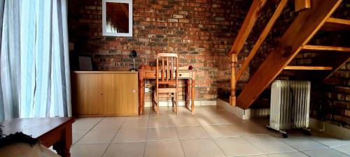 a room with a table and chairs and a brick wall at Cozy Cottage +/- 500m from the beach in Cape Town