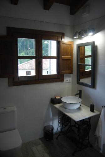 a bathroom with a white sink and two windows at El Molín de La Vega Agroturismo in Ribadesella