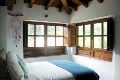 a bedroom with a bed and two windows at El Molín de La Vega Agroturismo in Ribadesella