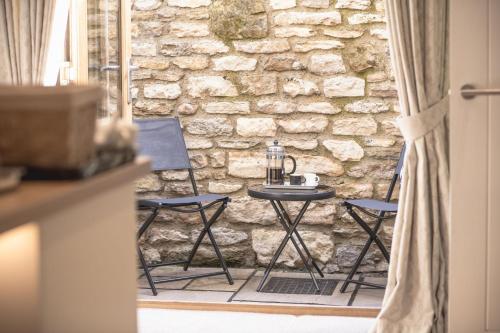 a table and chairs in front of a stone wall at Middle Row Cottage in Richmond