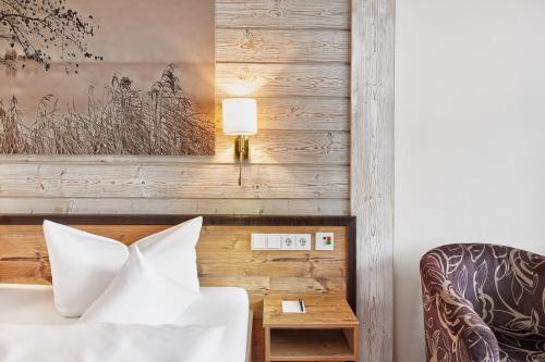 a bedroom with a bed and a chair at Königshof Hotel Resort in Oberstaufen