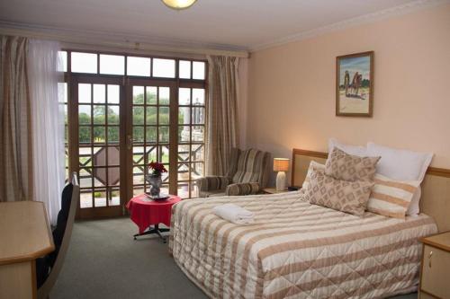 a bedroom with a bed and a desk and a window at Mountain View Hotel - Lesotho in Leribe