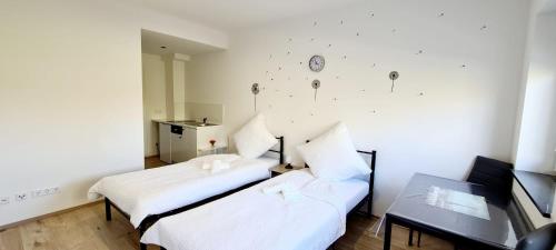 a room with two beds and a table and a clock on the wall at Pension Fürstenzell in Fürstenzell