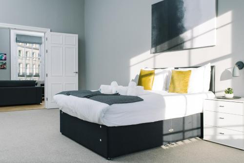 - une chambre dotée d'un grand lit avec des oreillers blancs et jaunes dans l'établissement ALTIDO Bold and Spacious 1bed home, near Haymarket train station, à Édimbourg