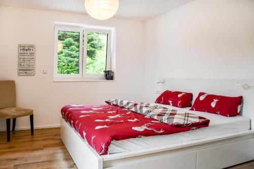 a white bed with red pillows and a window at Ferienhaus Wendelinus mit Pool & Sauna in Hausach