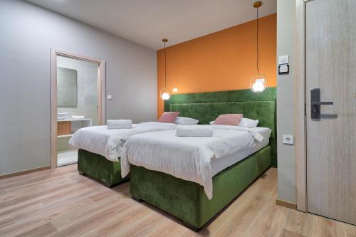 a bedroom with a large bed with a green headboard at Boutique Hotel St Georgije in Banja Luka