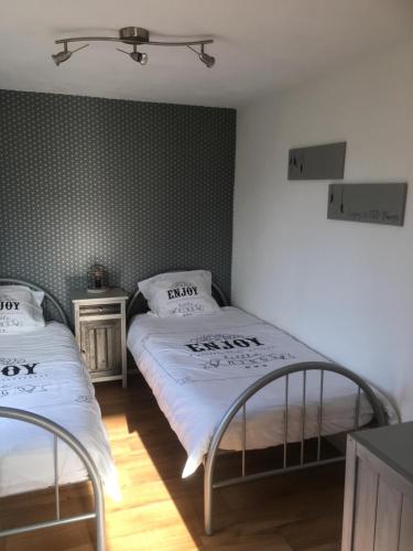 2 camas individuales en una habitación con papel pintado verde en La Sérénade, en La-Roche-en-Ardenne
