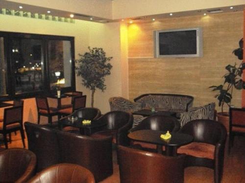 un restaurante con sillas y mesas de cuero y TV en Astoria Hotel Traditional, en Komotiní